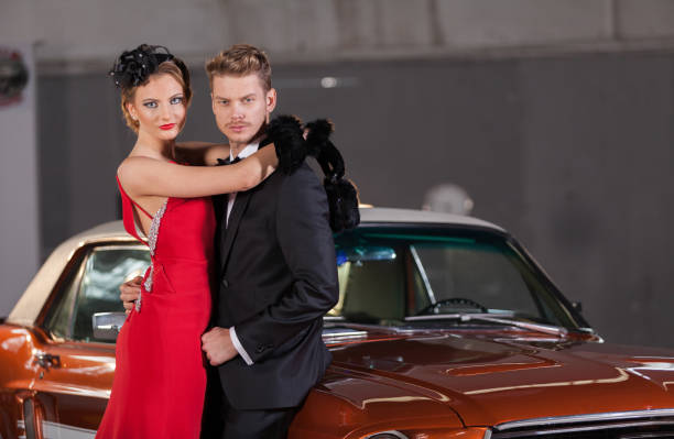 jeune couple d'élégance au garage avec sa voiture rétro - haute couture beautiful smoking beauty photos et images de collection