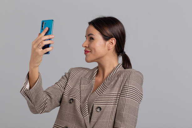 istock Woman in gray chequered suit taking selfie 1197009349