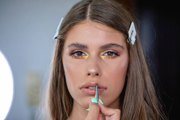 ragazza che guarda la telecamera mentre si fa il make-up - adolescence teenagers only teenager making a face foto e immagini stock