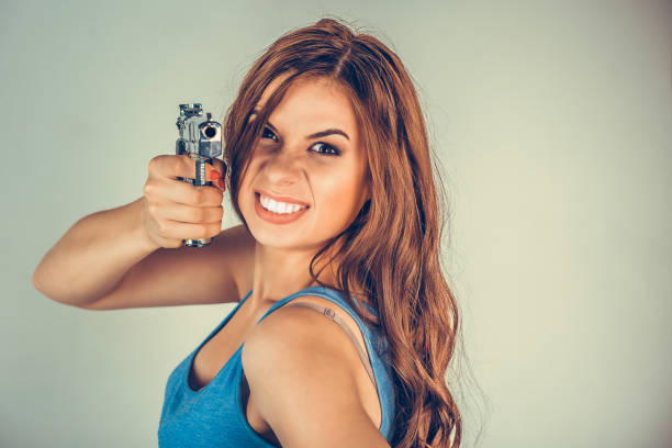 beautiful  young woman, girl with gun isolated on green wall. - handgun gun blue black imagens e fotografias de stock
