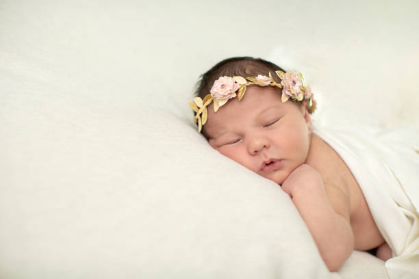 Sleeping newborn baby girl laying on a cream colored blanket with a floral crown on her head Sleeping newborn baby girl laying on a cream colored blanket with a floral crown on her head floral crown photos stock pictures, royalty-free photos & images