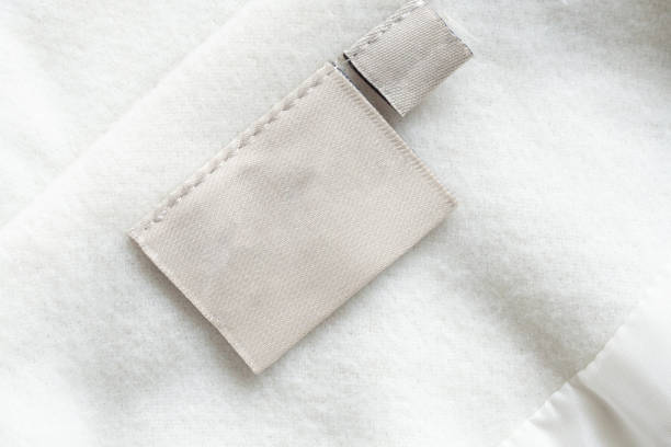 étiquette de vêtement de soin de blanchisserie sur la texture de tissu - garment photos et images de collection