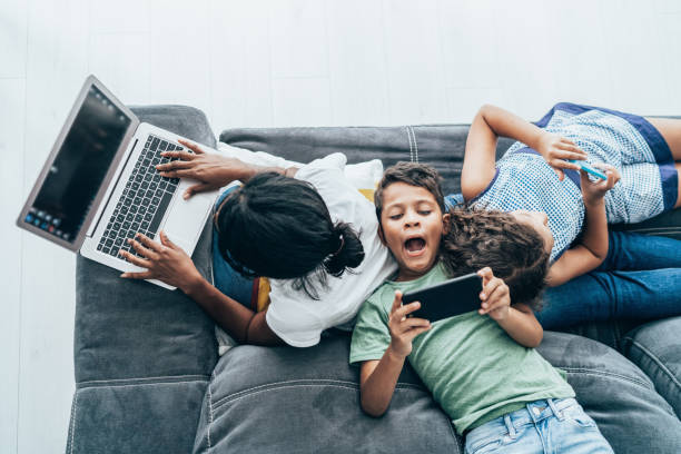 Mixed race family with digital devices Mixed race mother and her two children using digital devices at home family dependency mother family with two children stock pictures, royalty-free photos & images