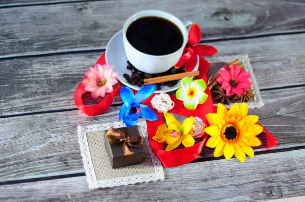 istock A white ceramic cup with coffee on a saucer decorated with cinnamon and anise, a small gift box on a napkin surrounded by flower buds. 1197025090