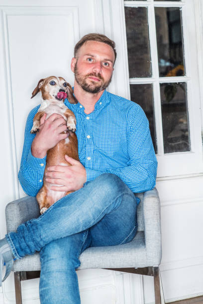 istock Young American Man with beard, wearing blue patterned shirt, jeans, sitting on chair at home in New York City, 1197026607