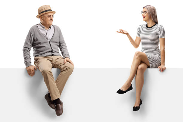 istock Elderly man and a young woman talking while sitting on a blank panel 1197028313