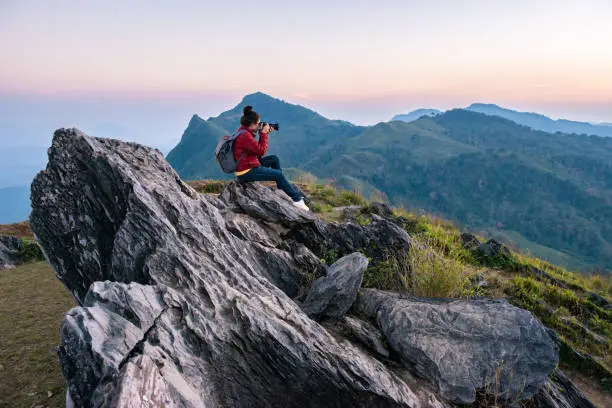 Photo of Tourist woman take a photographs of beautiful landscape of Doi Pha Tang in Chiang Rai province of Thailand at sunset.