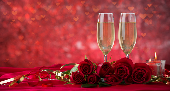 Valentine's Day dinner. Champagne glass and roses on velvet drape