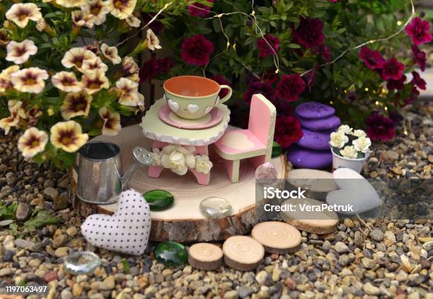Tiny Table Chair And Cup By Flowerpot With Petunia Flowers In The Garden Stock Photo - Download Image Now