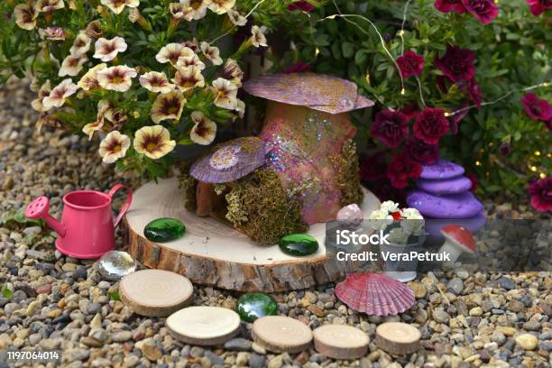 Funny Fairy Dollhouse On Wooden Planks By Flowerbed With Petunia Flowers In The Garden Stock Photo - Download Image Now