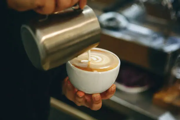 Photo of Barista pours milk into coffee