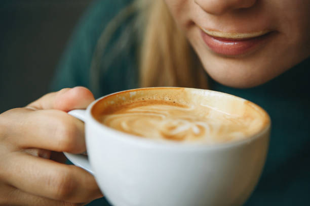 Close up girl is drinking coffee Close up girl is drinking coffee. She has coffee foam on her lips and she smiles. She is enjoying her morning cappuccino. cappuccino coffee froth milk stock pictures, royalty-free photos & images