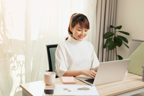 istock Cheerful young Asian woman working at home with computer 1197065454