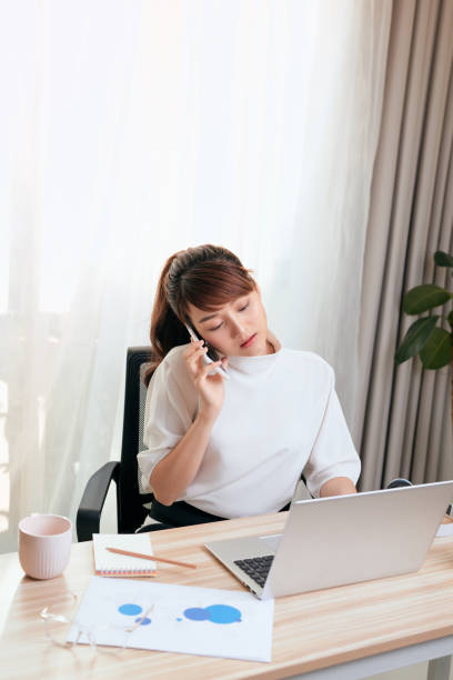 istock Asian Woman working on laptop at office while talking on phone 1197066144