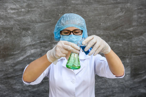 istock Woman chemist with test tubes and protective uniform making experiment with two substance 1197066404