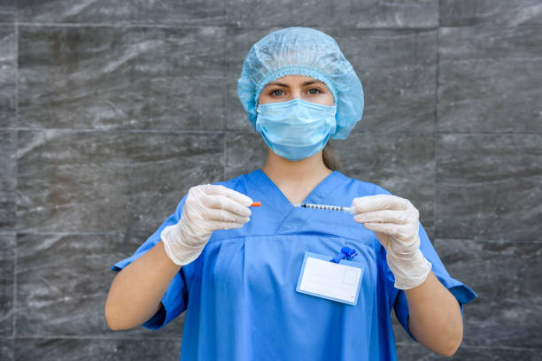 medizin. arzt frau in schutzuniform mit maske auf gesicht halten spritze - surgical glove human hand holding capsule stock-fotos und bilder