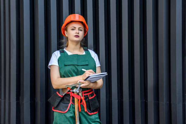 istock Woman worker in coverall with tool belt posing near grey wall 1197069766
