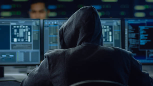 istock Hooded IT Hacker or Specialist Works on a Personal Computer With Display Showing Software Program with Coding Language Interface 1197070912