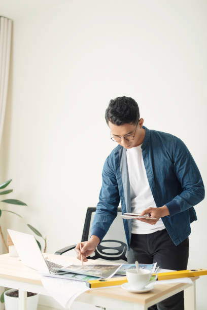 istock Young engineer. Successful busy man drawing something while working in the office 1197075779