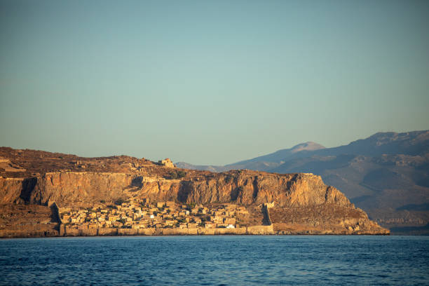 Small settlement Monomvasia located on small rocky peninsula next to Peloponnese, Greece. View from the sea at morning, with soft sunlight