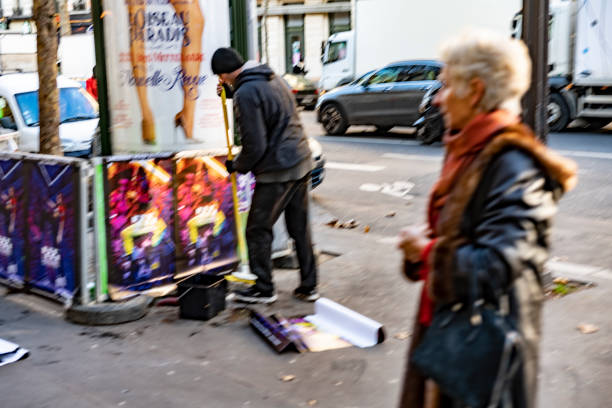 2019 Paris Bus stop cleaning. A cleaning contractor using pressure hose to clean a bus stop on a street near the Champs Elysees, Paris, France.