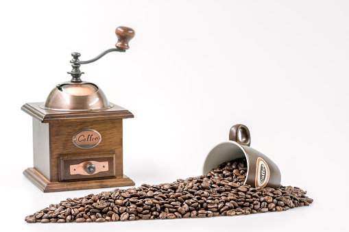 Top view of an electric coffee grinder with coffee grains poured into it. Blurred background with grains of coffee.
