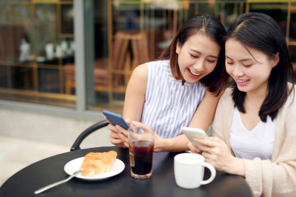 istock Happy girls using mobile in cafeteria. 1197087689