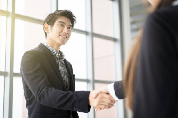 Young businesspeople Businessman and businesswoman doing a handshake after business talk.  Concept of professional business people. job fair stock pictures, royalty-free photos & images