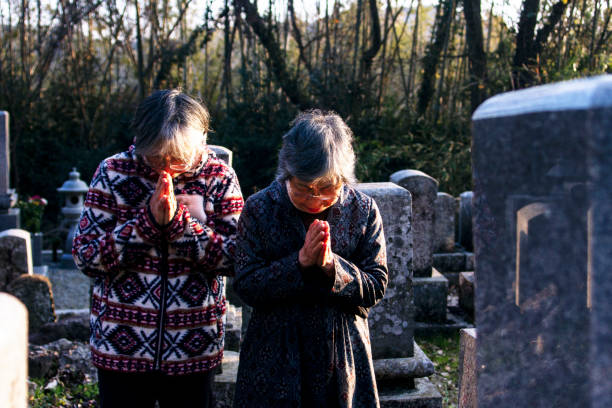 deux femmes japonaises aînées ont mis leurs mains ensemble dans le cimetière - japan serious family senior adult photos et images de collection