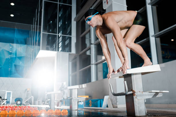 istock shirtless swimmer standing in starting pose on diving block 1197099715