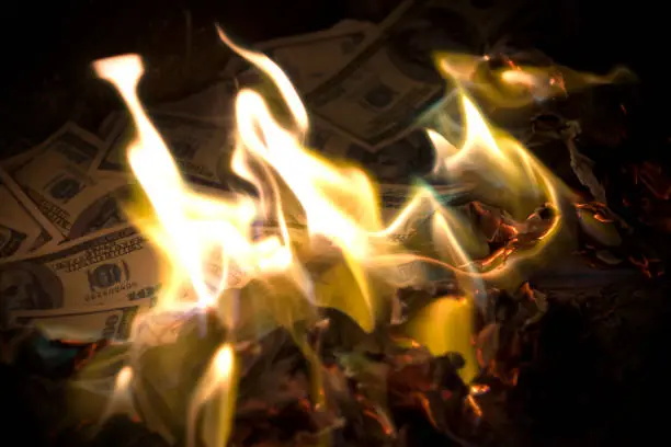 Photo of US Dollars in fire. One hundred dollar banknotes burning. Dollars in flames..