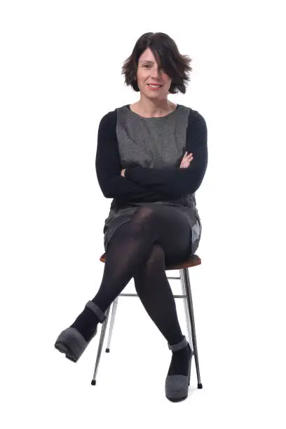 woman in dress sitting on a white background lengs crossed and arms crossed