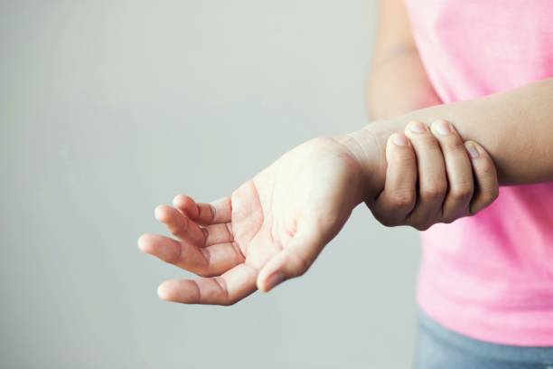 frauen rosa hemd mit armschmerzen. gesundheitsversorgung und medizinisches konzept. - pain joint human hand arthritis stock-fotos und bilder