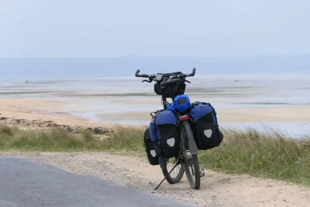 Photo of A travel bike stands on a coast at low tide.