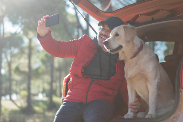 istock Man Making Selfie With His Dog on the car trunk 1197108394