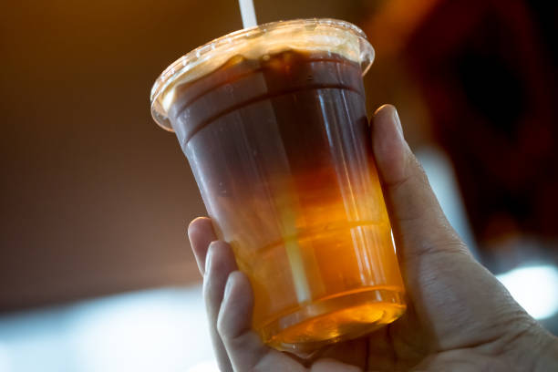 Glass of espresso shot mixed with soda or sparkling water in hand