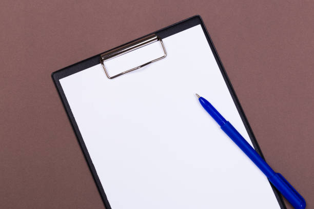 istock Clipboard with white sheet and pen on a colored background. View from above. space for text 1197110842