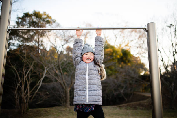 Girl playing with horizontal bar in winter park Girl playing with horizontal bar in winter park horizontal bar stock pictures, royalty-free photos & images