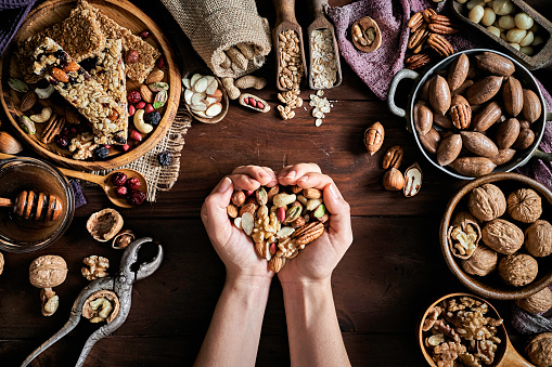 Woman hands holding a variety of dried fruit and nuts on a table in a old fashioned rustic kitchen