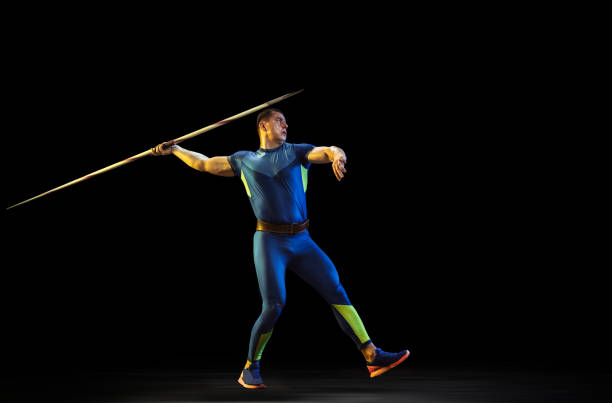 istock Male athlete practicing in throwing javelin isolated on black studio background in neon light 1197113213