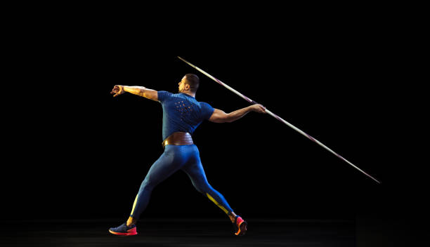 istock Male athlete practicing in throwing javelin isolated on black studio background in neon light 1197113231