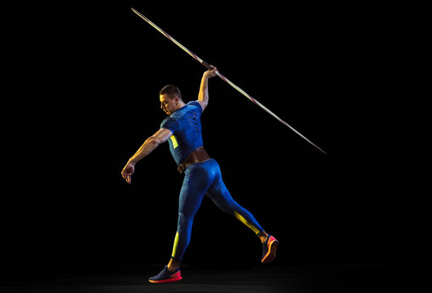 istock Male athlete practicing in throwing javelin isolated on black studio background in neon light 1197113234
