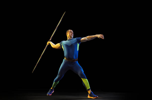 istock Male athlete practicing in throwing javelin isolated on black studio background in neon light 1197113245