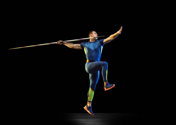 istock Male athlete practicing in throwing javelin isolated on black studio background in neon light 1197113289