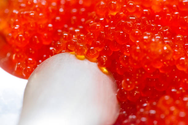 Glass jar with red caviar on a wooden surface. Largest species. Horizontal photography