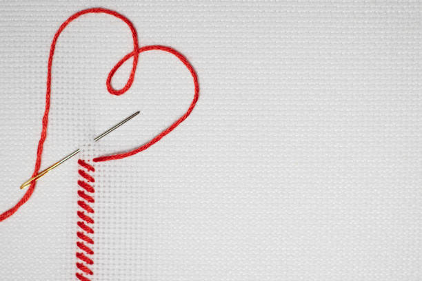 bordado com costura vermelha na forma de um coração em uma tela branca - red stitches - fotografias e filmes do acervo