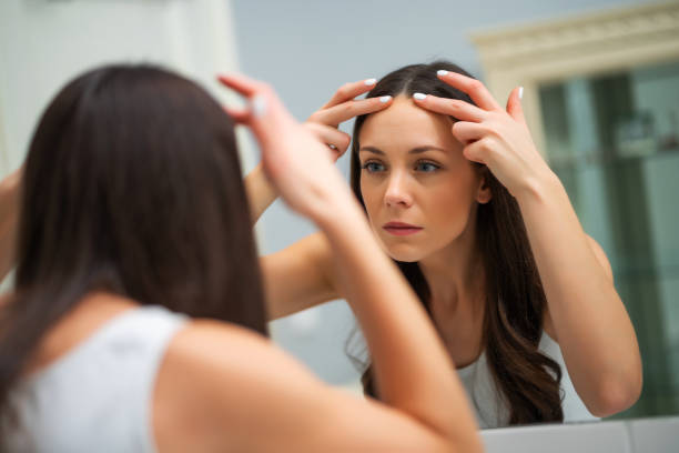 istock Woman looking at wrinkles on her forehead 1197121829