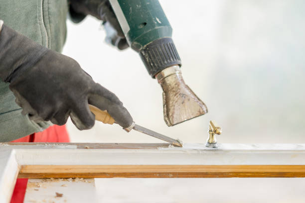 istock Man removes the old paint from a window frame with chess and warm air 1197129049