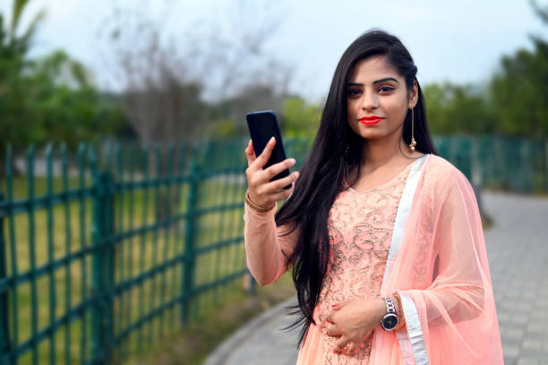istock Young Asian / Indian woman looking at camera while taking selfie with smartphone 1197130949