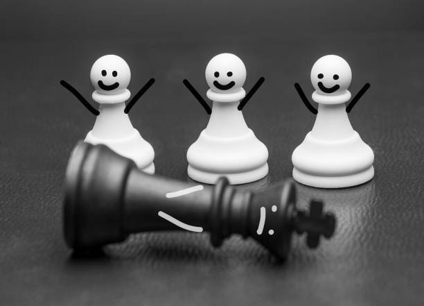 Chess piece pawns with smiles and arms rejoicing Three chess piece pawns with smiles and raised arms rejoicing at a fallen king in front of them in a conceptual image funeral planning stock pictures, royalty-free photos & images